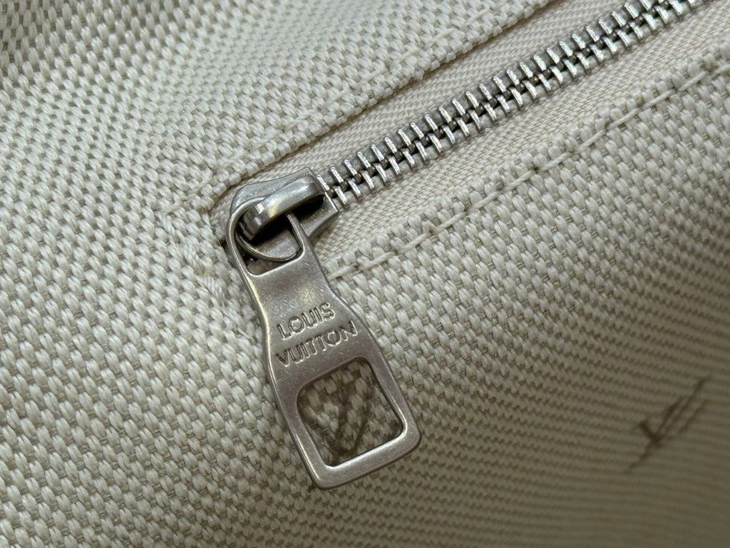 Beige Louis Vuitton bag zipper pull on textured canvas with monogram marks