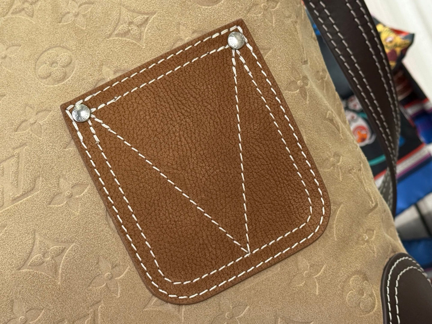 Louis Vuitton monogram bag flap with brown patch, silver studs, and white stitching