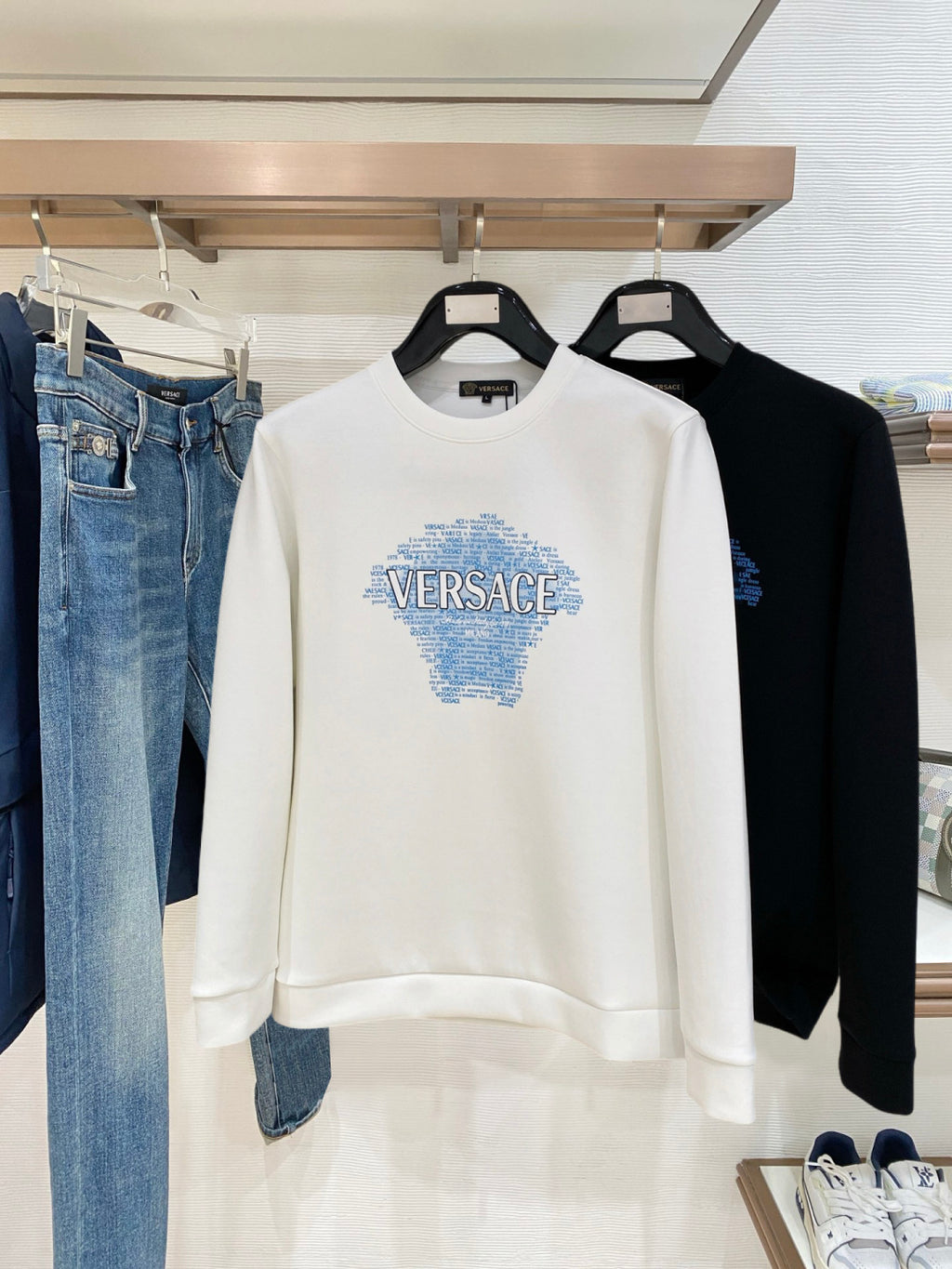 White crewneck sweatshirt with blue Versace Medusa logo print on chest.