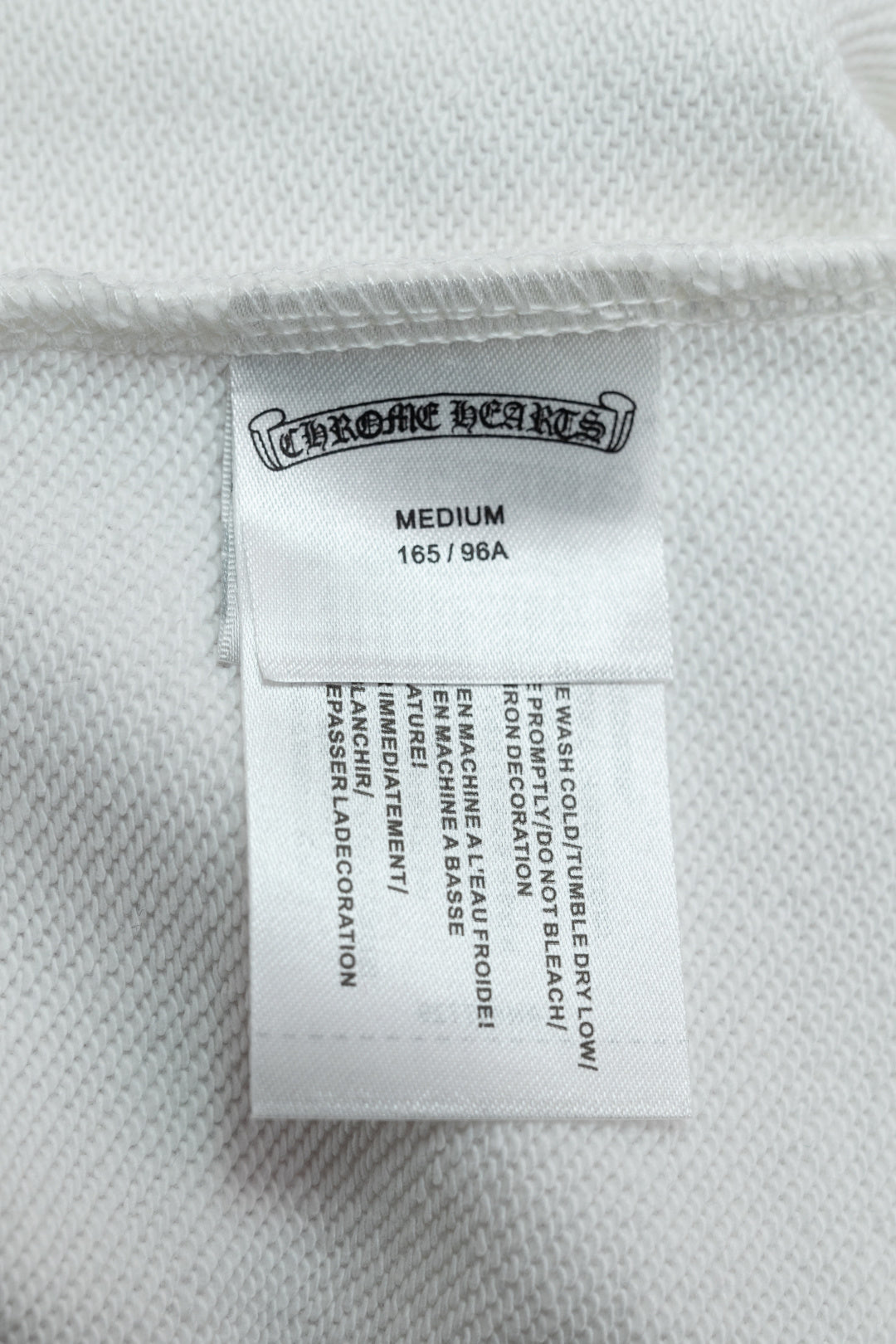 White hoodie size label inside garment with MEDIUM and care information