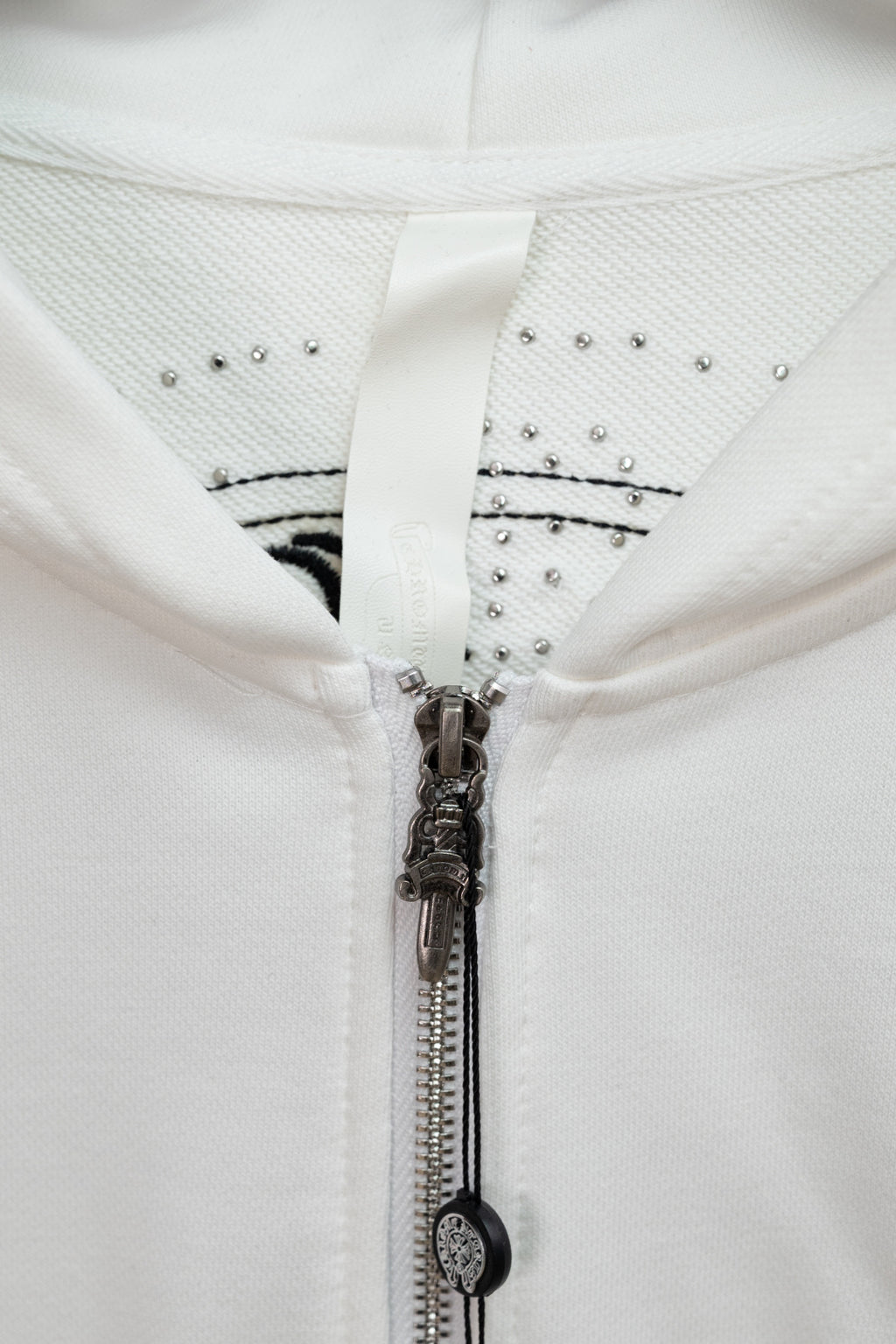 White hoodie hood and zipper with studded trim and metallic zipper pull detail