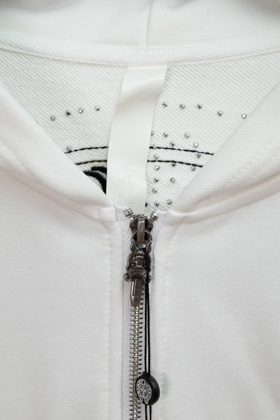 White hoodie hood and zipper with studded trim and metallic zipper pull detail