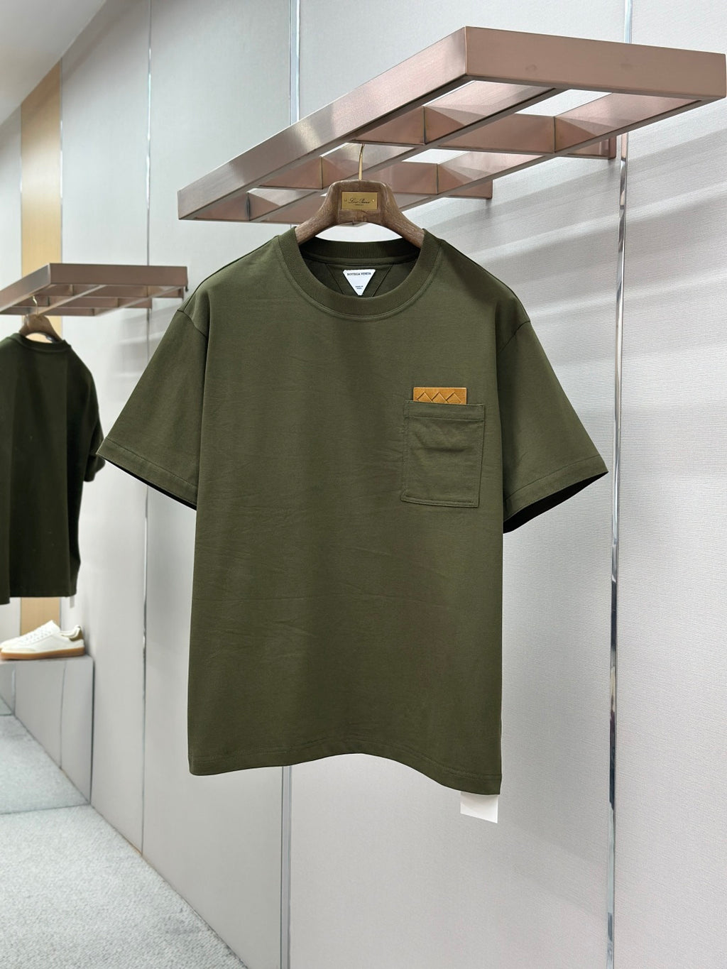 Olive green crew-neck T-shirt with chest pocket and rectangular logo patch