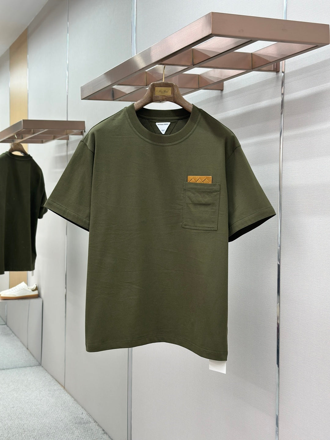 Olive green crew-neck T-shirt with chest pocket and rectangular logo patch
