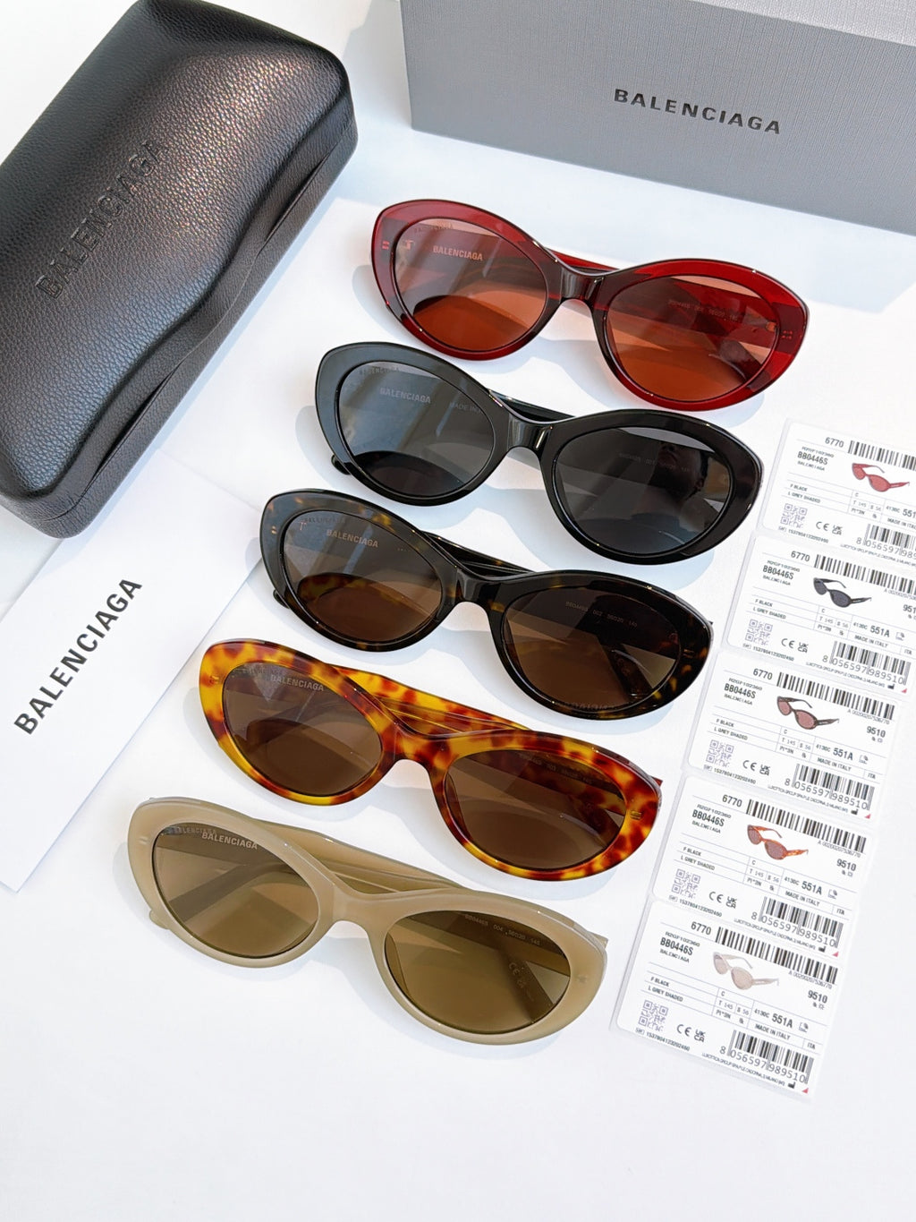 Sunglasses assortment featuring red, black, tortoise, and beige frames with tinted lenses.