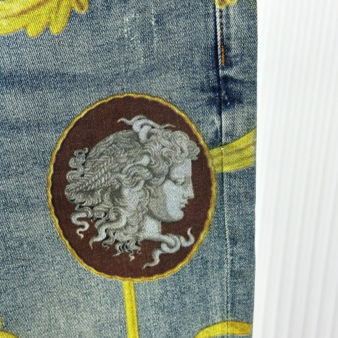 Versace jeans detail: brown medallion with gray face, outlined in gold on denim