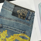 Blue denim jeans back waistband with black logo patch and gold Medusa emblem.
