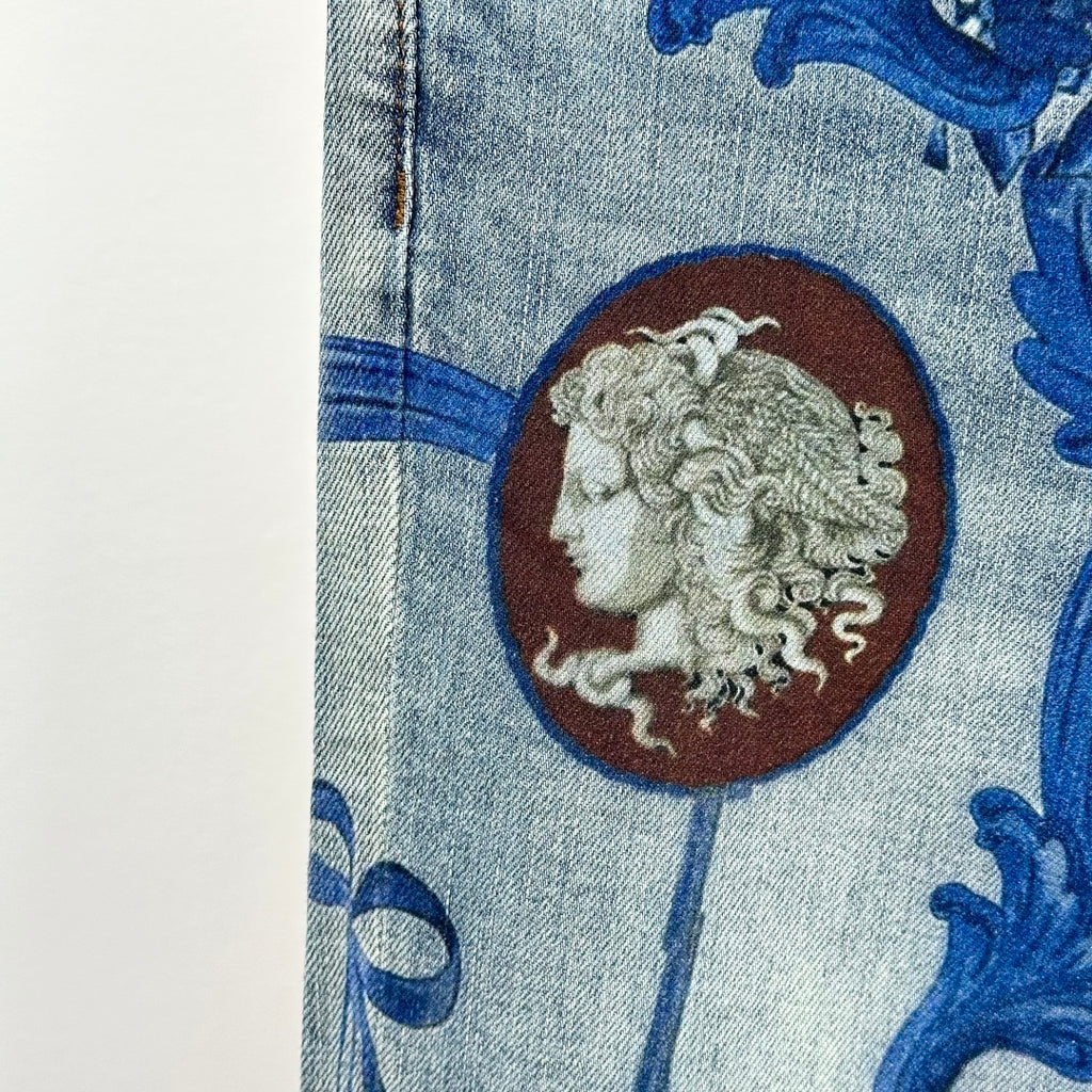 Denim jeans close-up: blue baroque print and large lion medallion patch