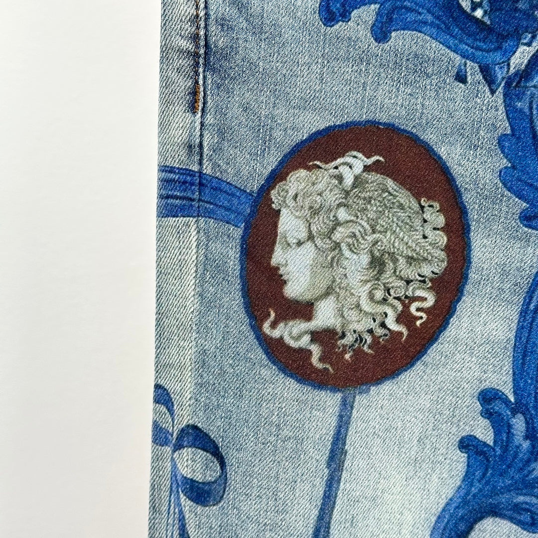 Denim jeans close-up: blue baroque print and large lion medallion patch