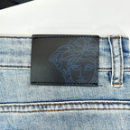 Versace leather-look logo patch on light-wash denim jeans waistband