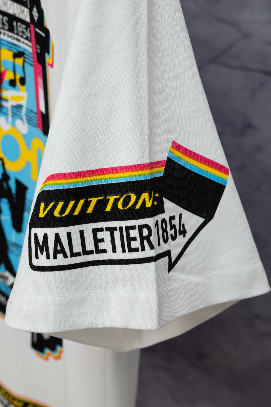 White Louis Vuitton T-shirt sleeve cuff with rainbow stripe and “VUITTON” badge