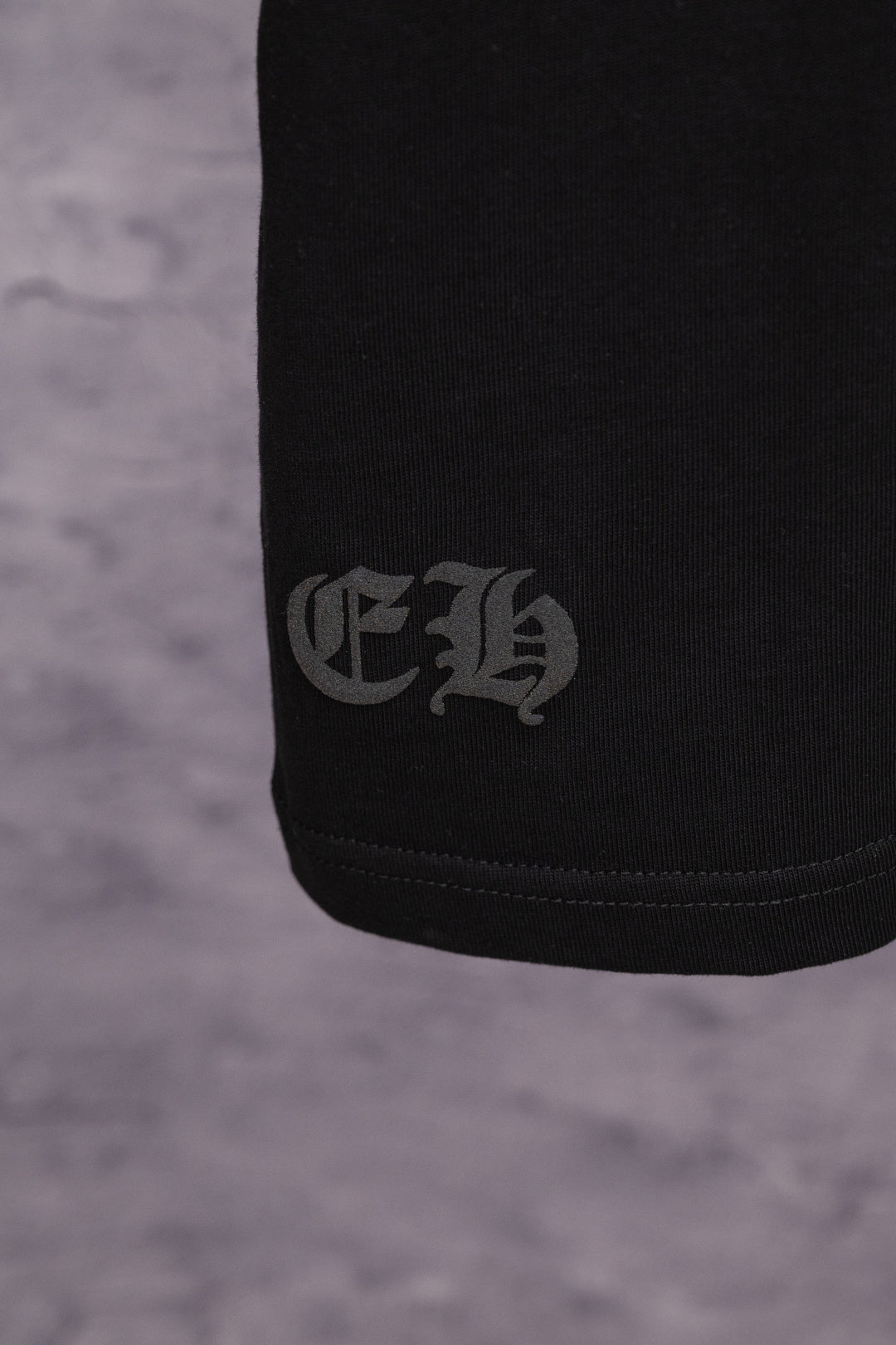 Black T-shirt with small dark logo print at side hem