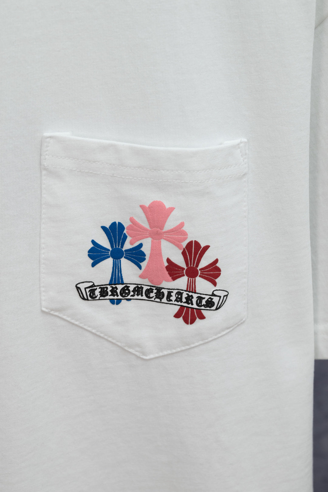 White T-shirt chest pocket with colorful floral emblem and logo text