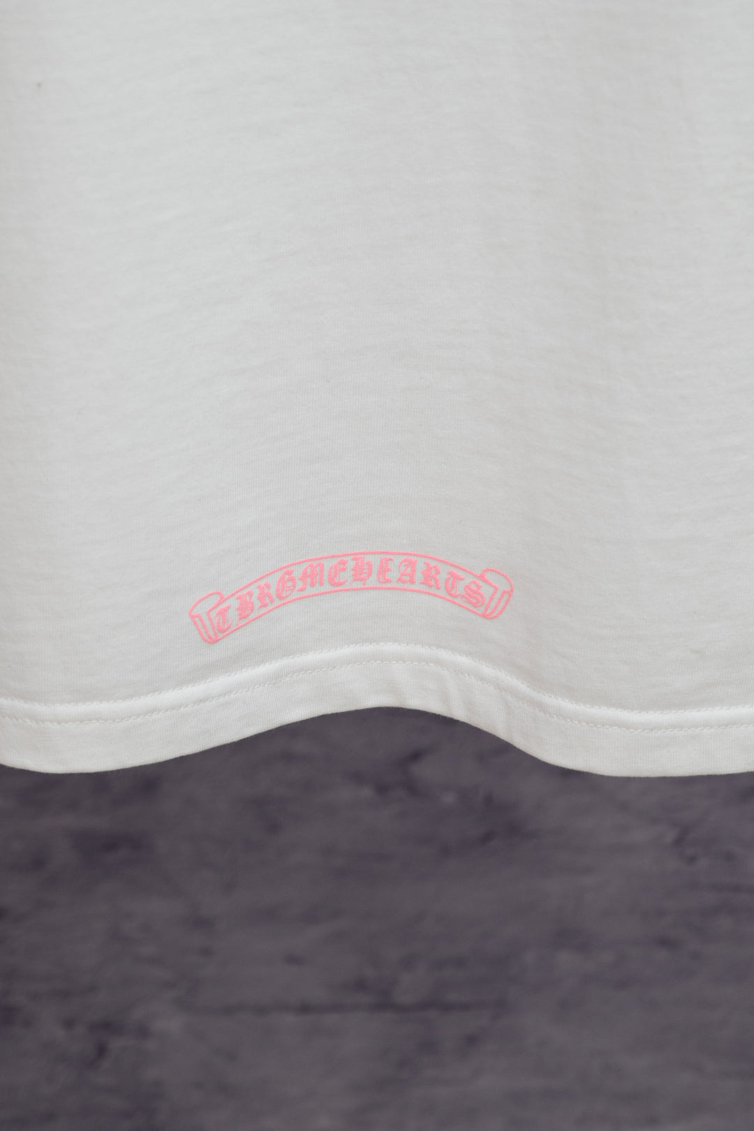 White T-shirt hem with small pink back graphic print