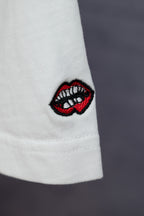 White T-shirt sleeve with red-and-black embroidered lip logo patch