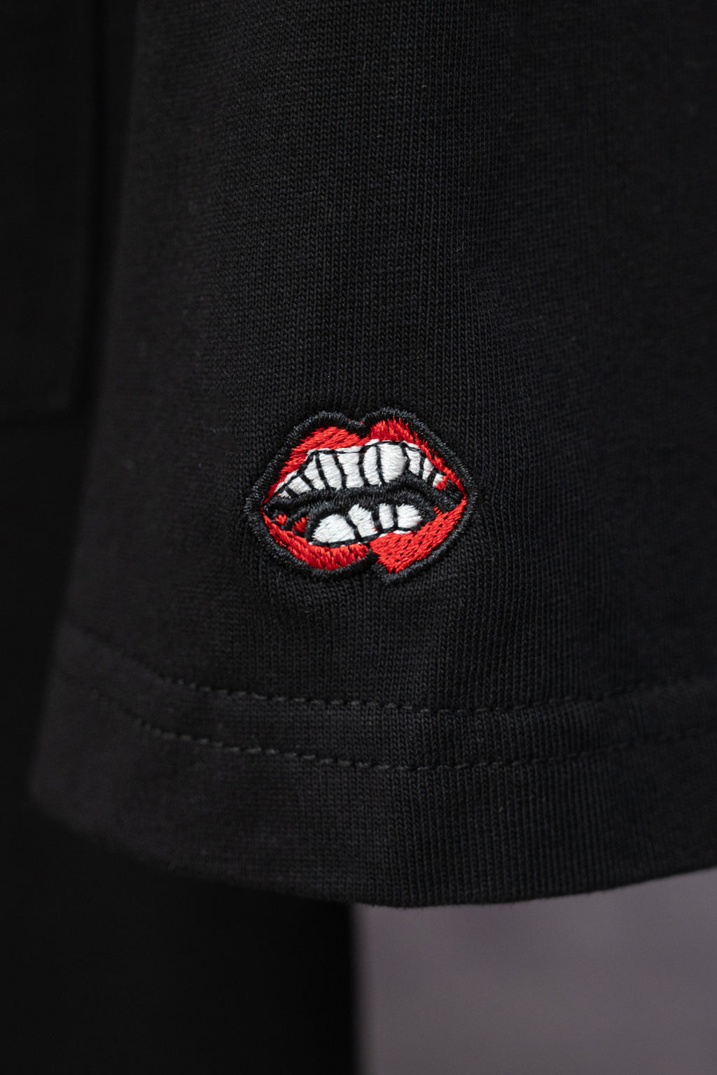 Black short-sleeve T-shirt with red and white lip embroidered patch on sleeve