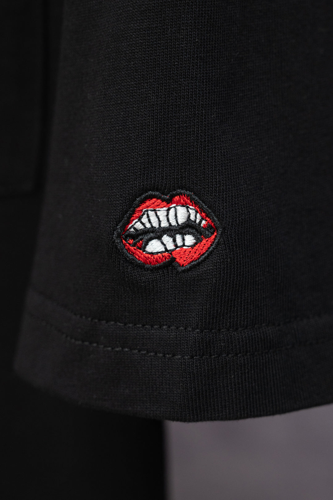 Black short-sleeve T-shirt with red and white lip embroidered patch on sleeve