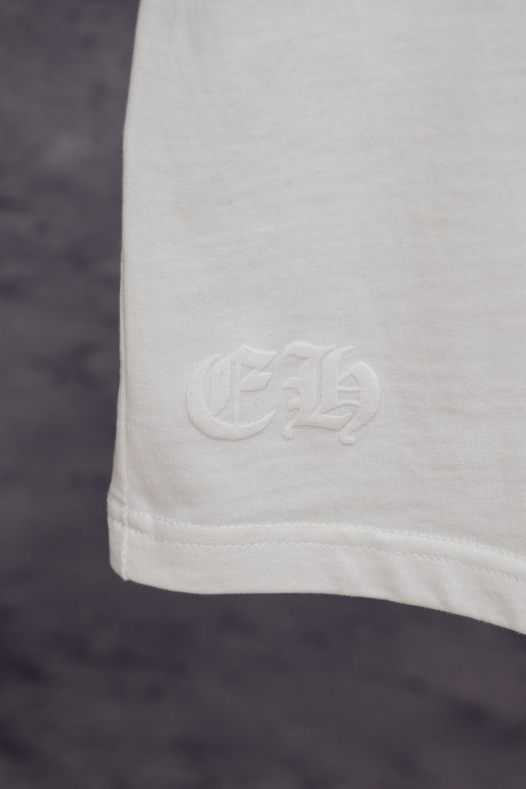 White T-shirt lower hem with small embossed logo detail