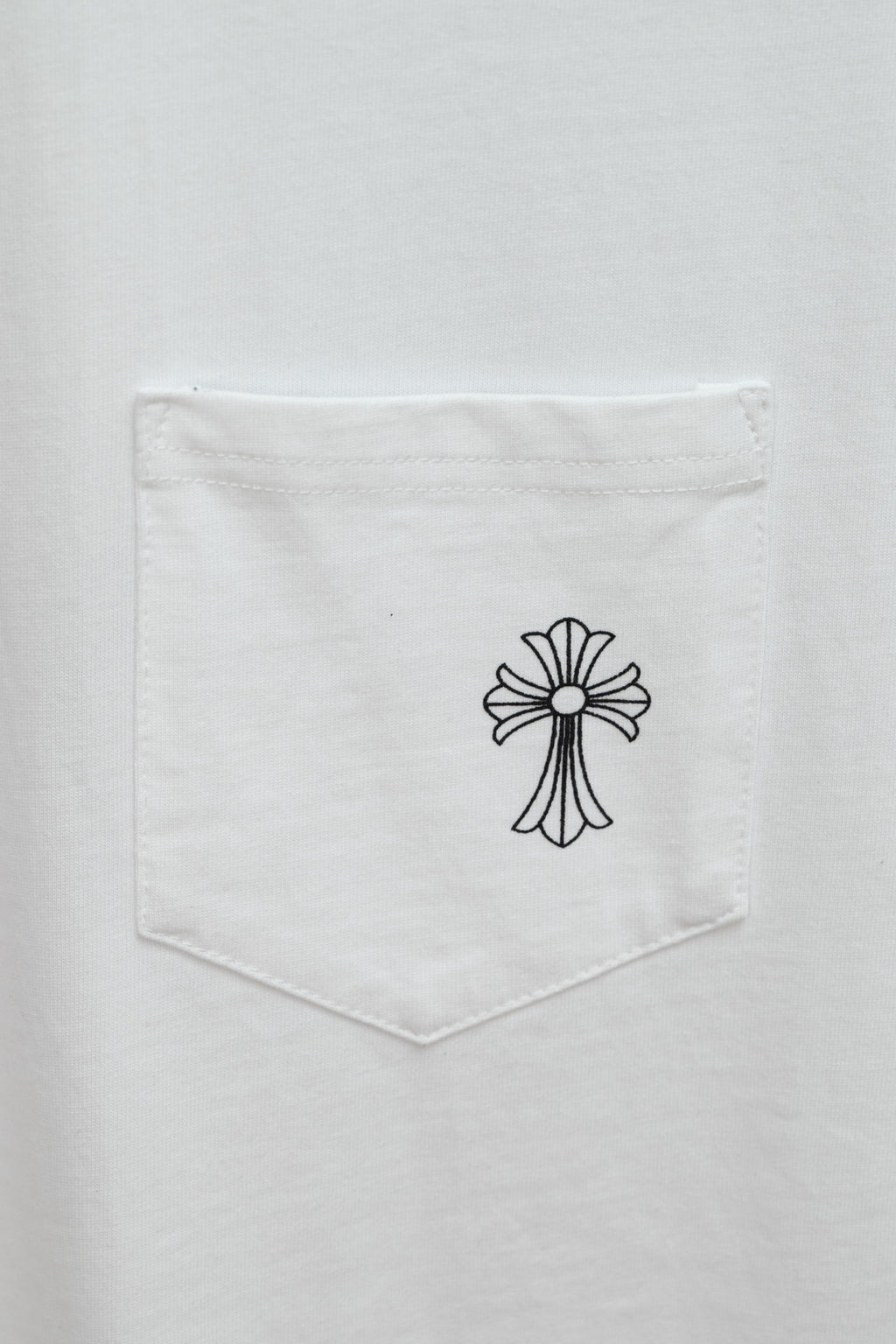White T-shirt chest pocket with small black cross graphic