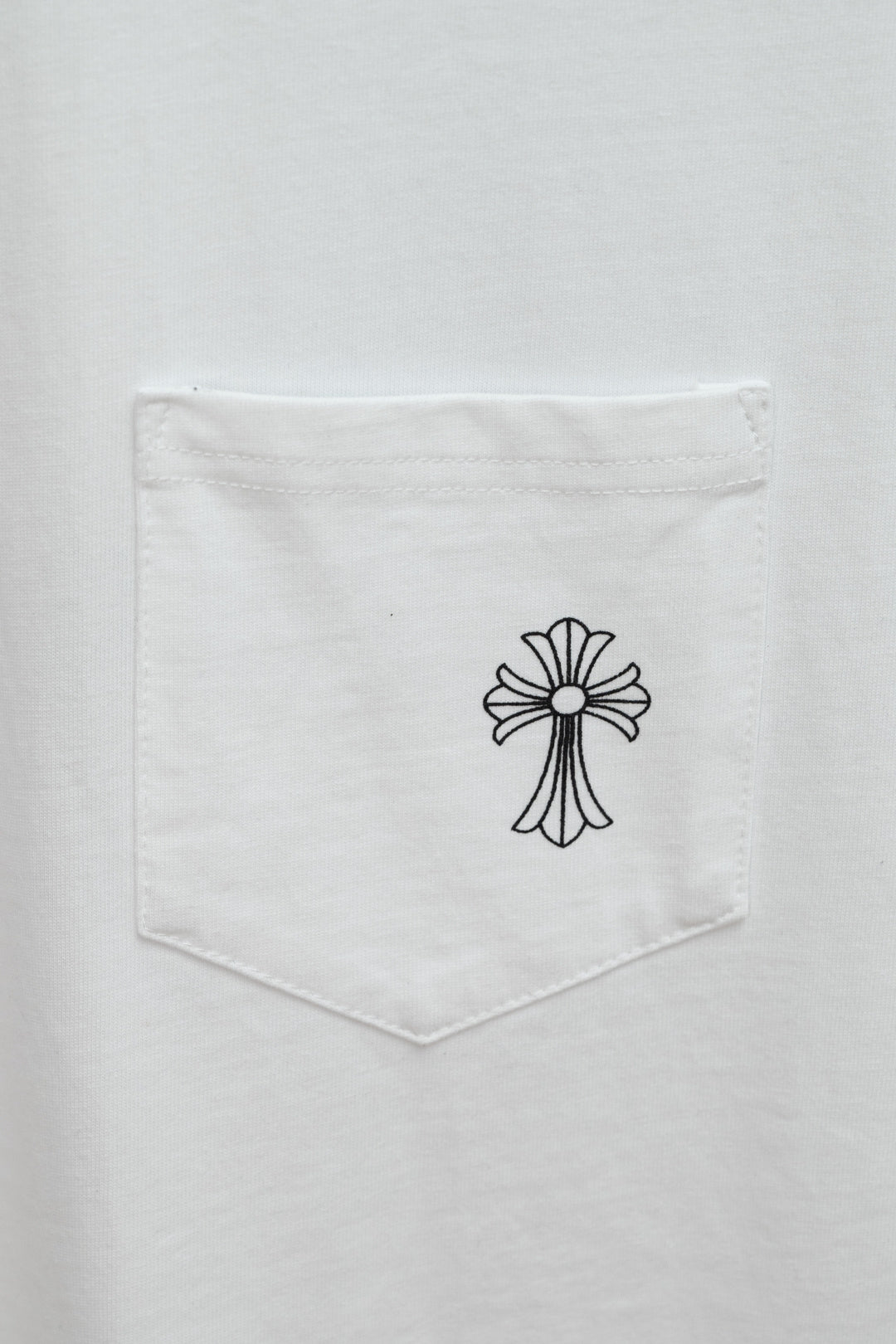 White T-shirt chest pocket with small black cross graphic