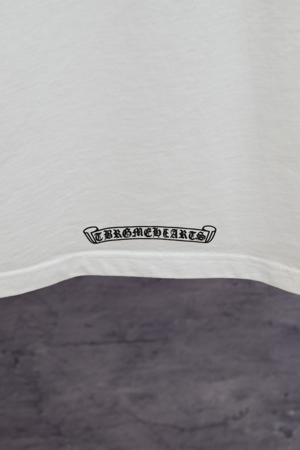 White T-shirt hem with small black logo badge
