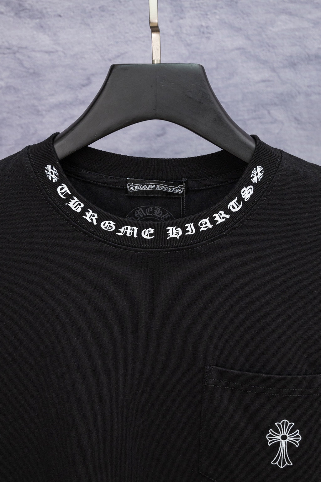 Black T-shirt neckline with printed logo and small chest pocket detail