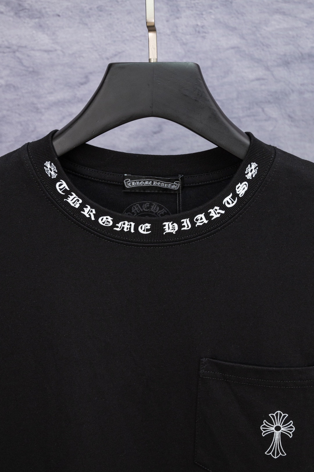 Black T-shirt neckline with white arched text graphic and brand tag label