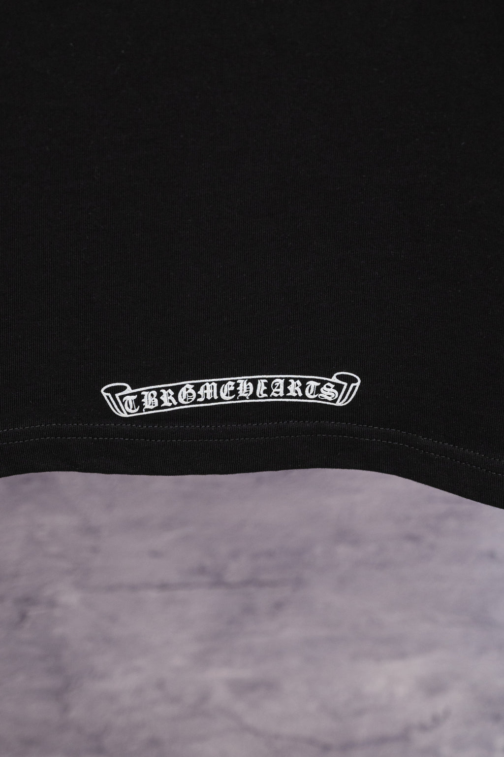 Black T-shirt hem band with small white arched logo text