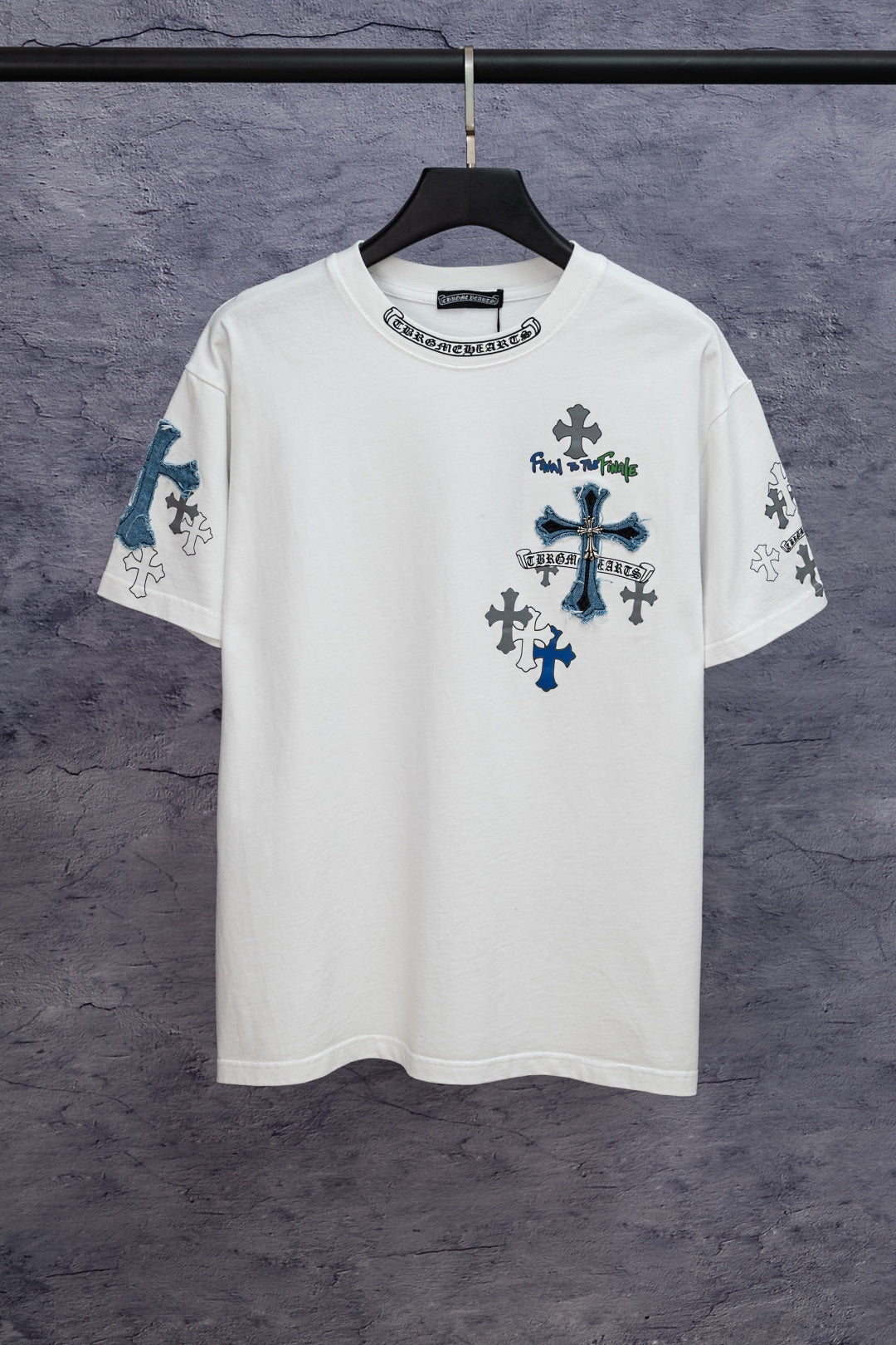 White short-sleeve T-shirt with large blue cross graphic and small dark cross icons