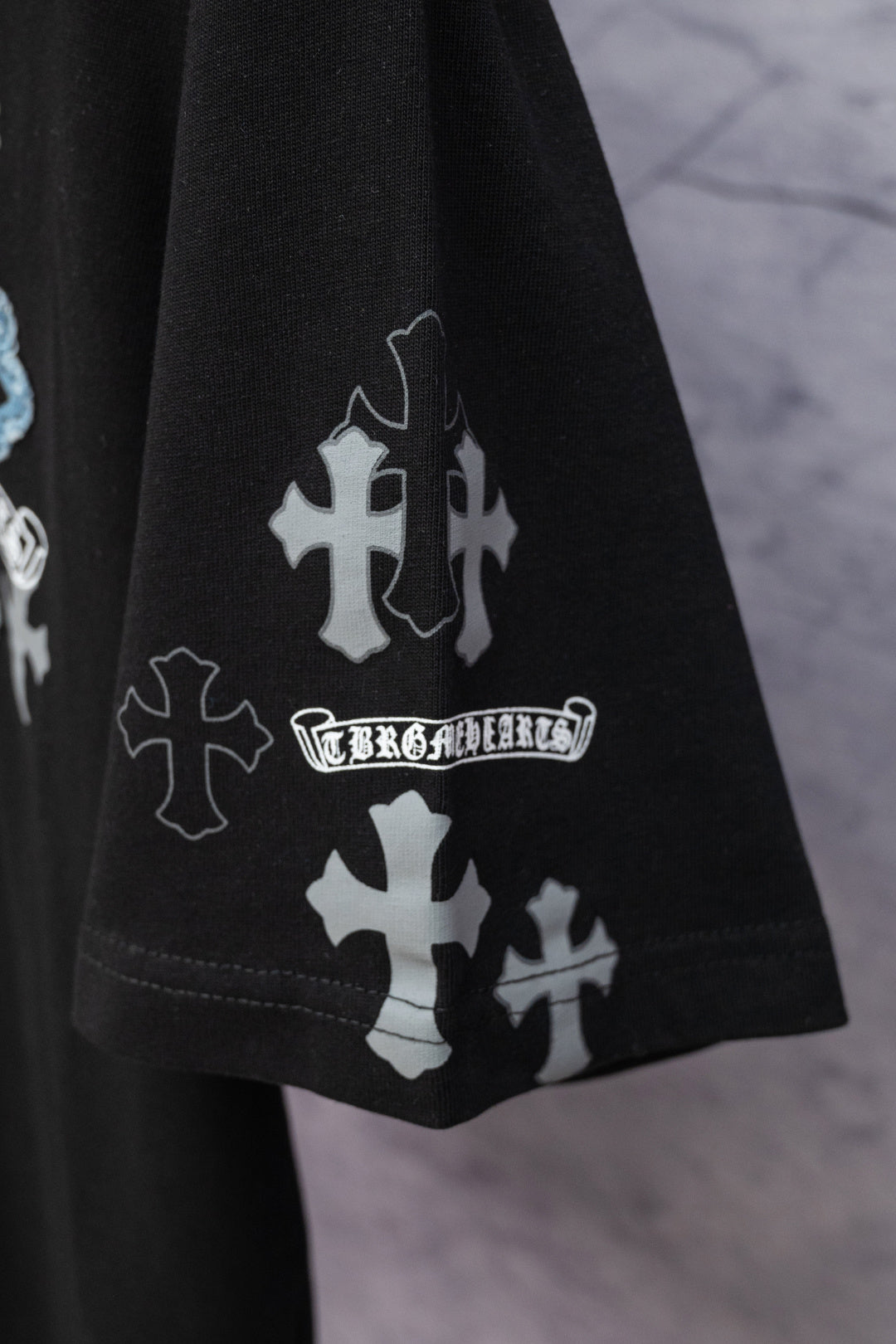 Black T-shirt hem and sleeve print with cross icons and small text graphic