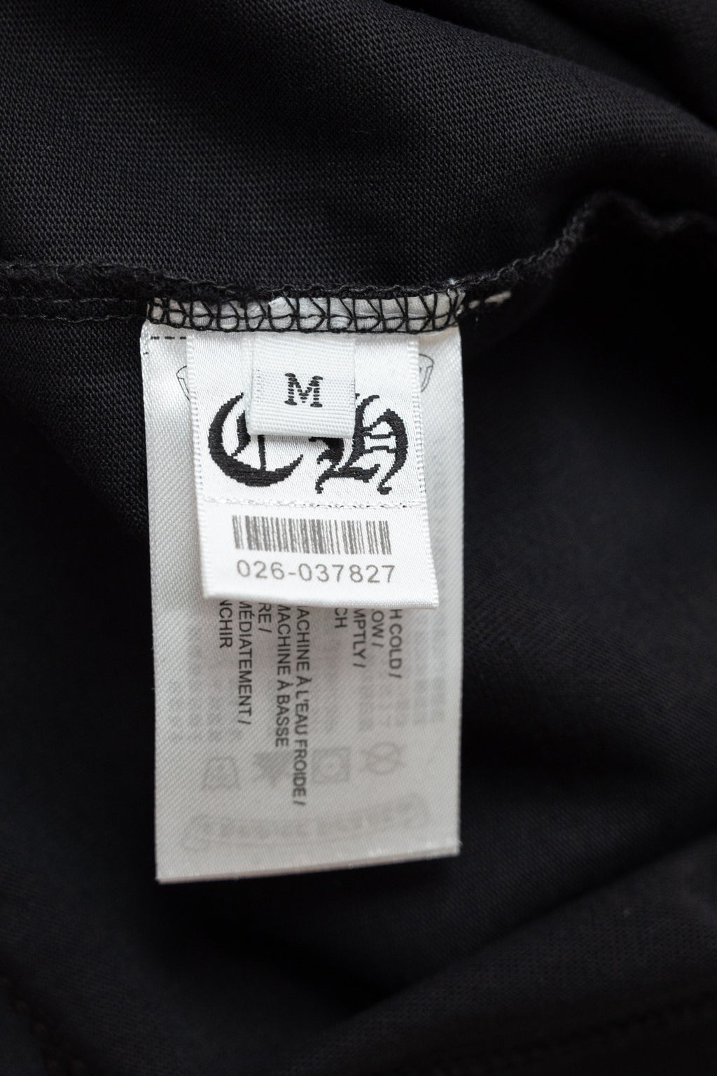 Size M clothing label inside black T-shirt with care information
