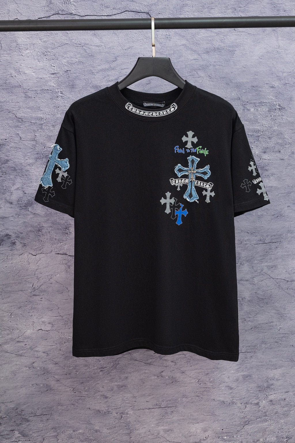 Black graphic T-shirt with blue cross artwork on chest, hanging on a black hanger