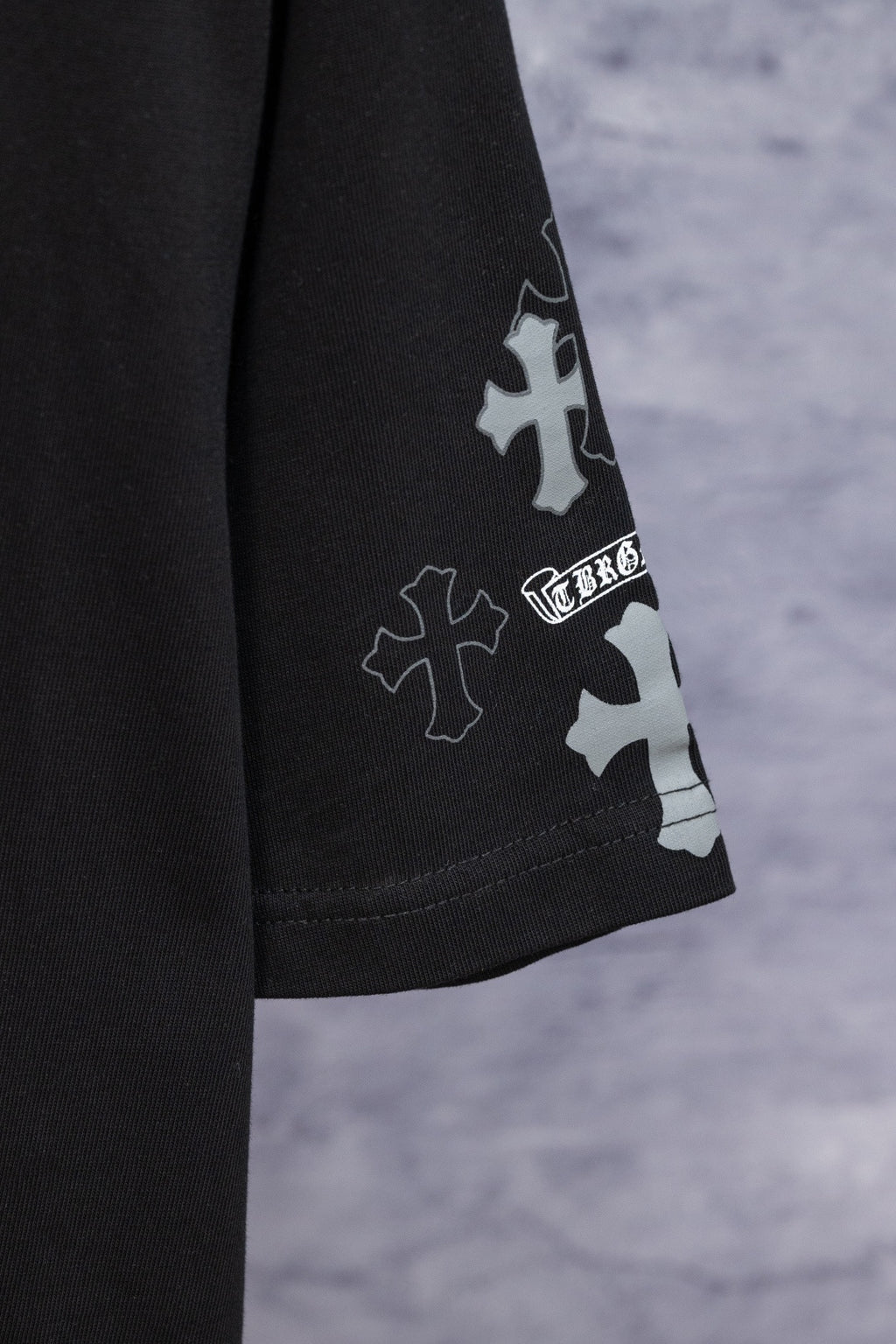 Black T-shirt sleeve with blue and white cross patch graphic