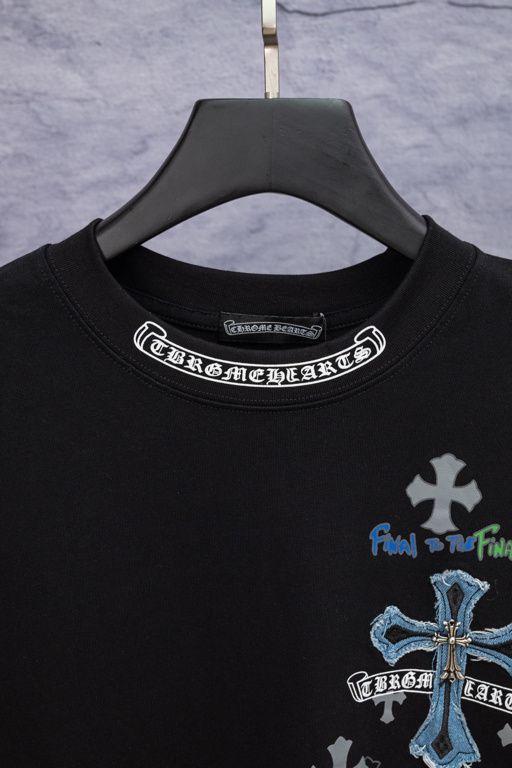 Black T-shirt neckline with white circular text graphic, blue and gray chest logo