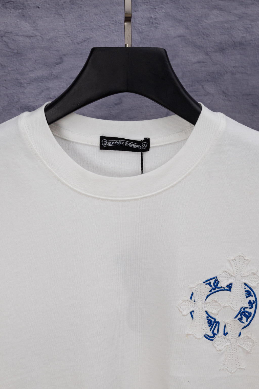 White crew-neck T-shirt with black neck label and blue logo patch
