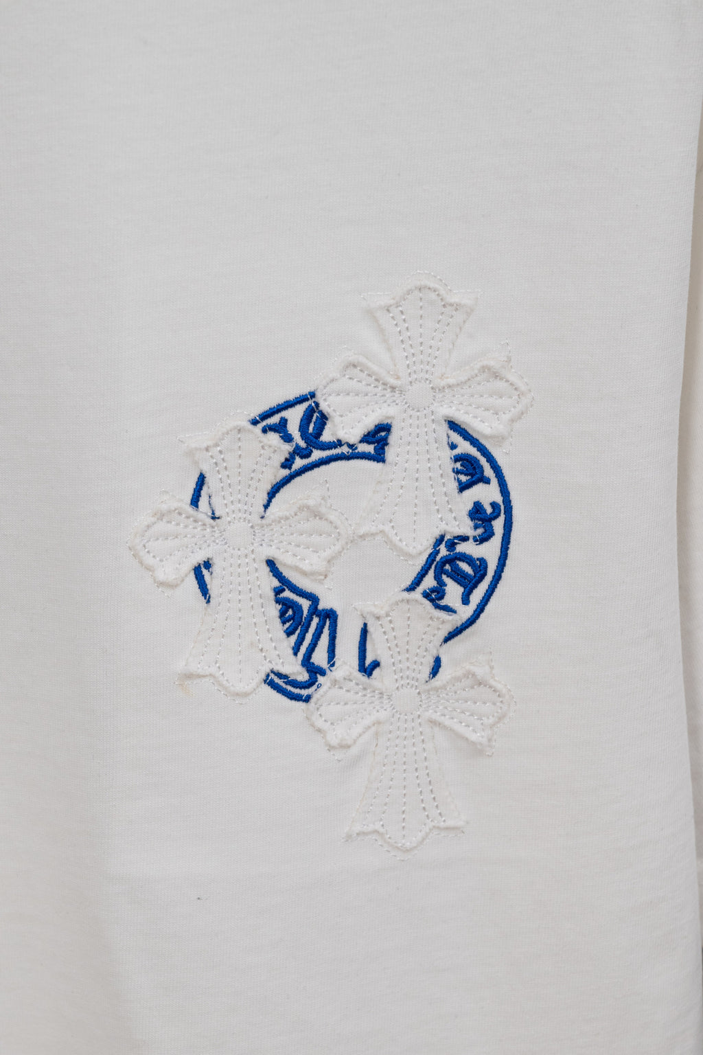 White T-shirt with blue circular embroidery and white flower appliques