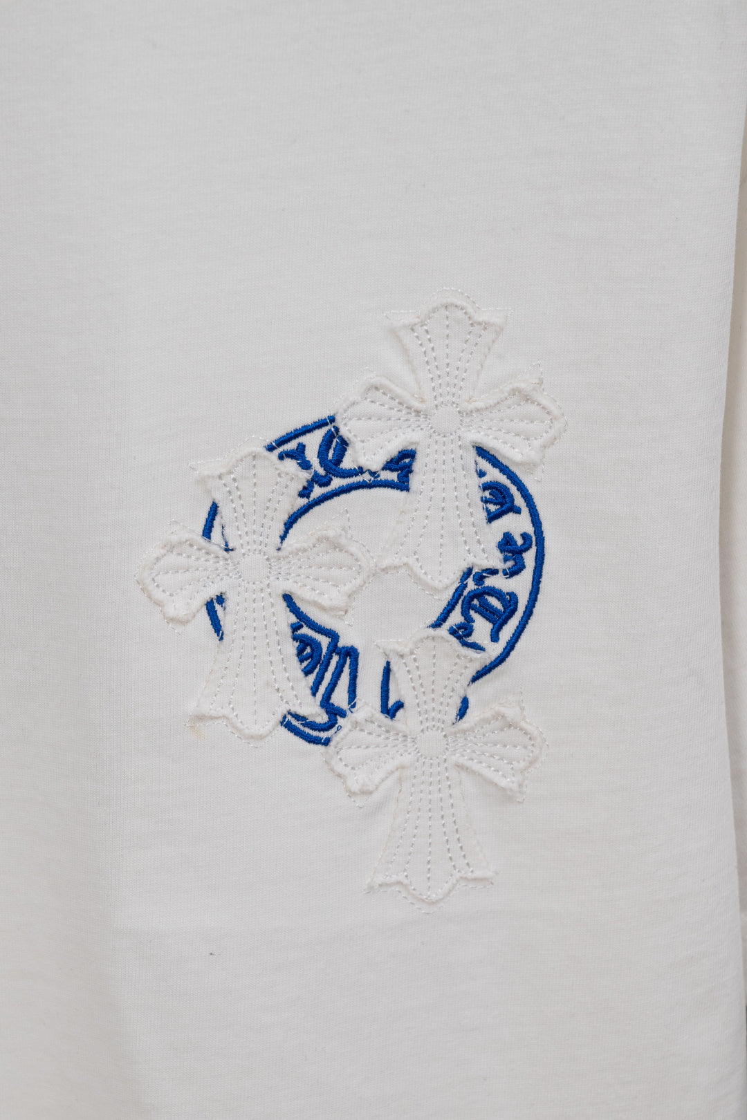 White T-shirt with blue circular embroidery and white flower appliques