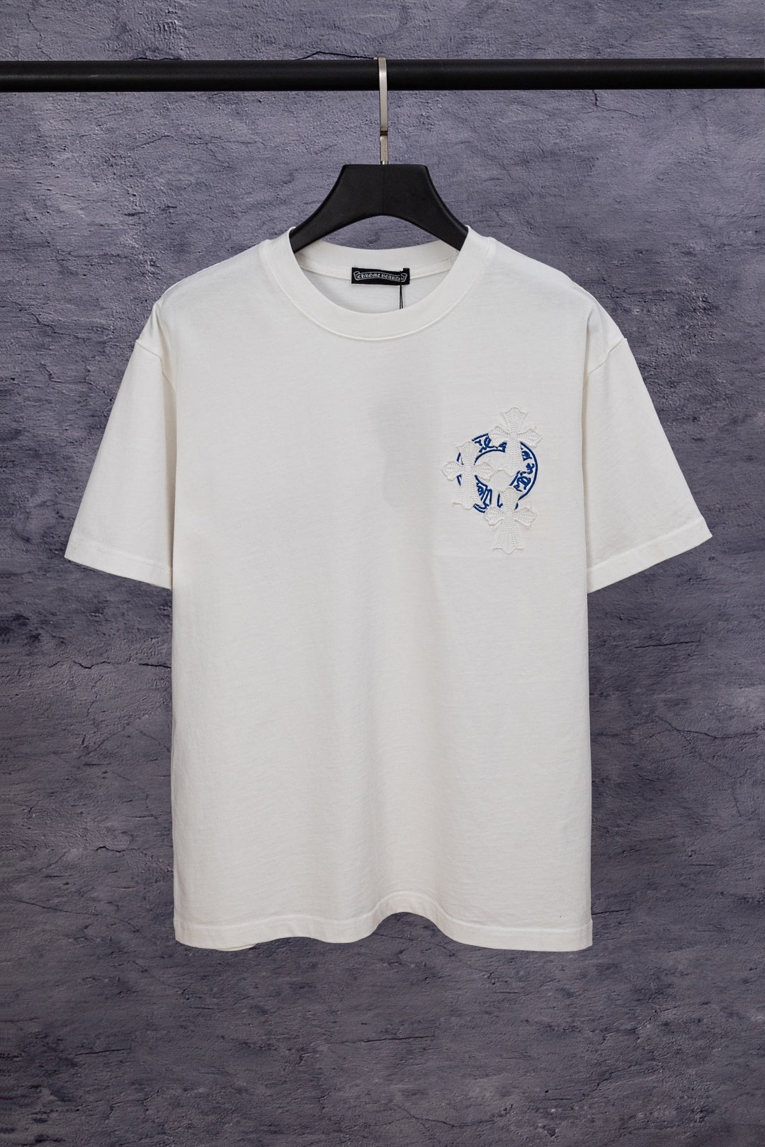 White short-sleeve T-shirt with blue chest graphic and small flower embroidery