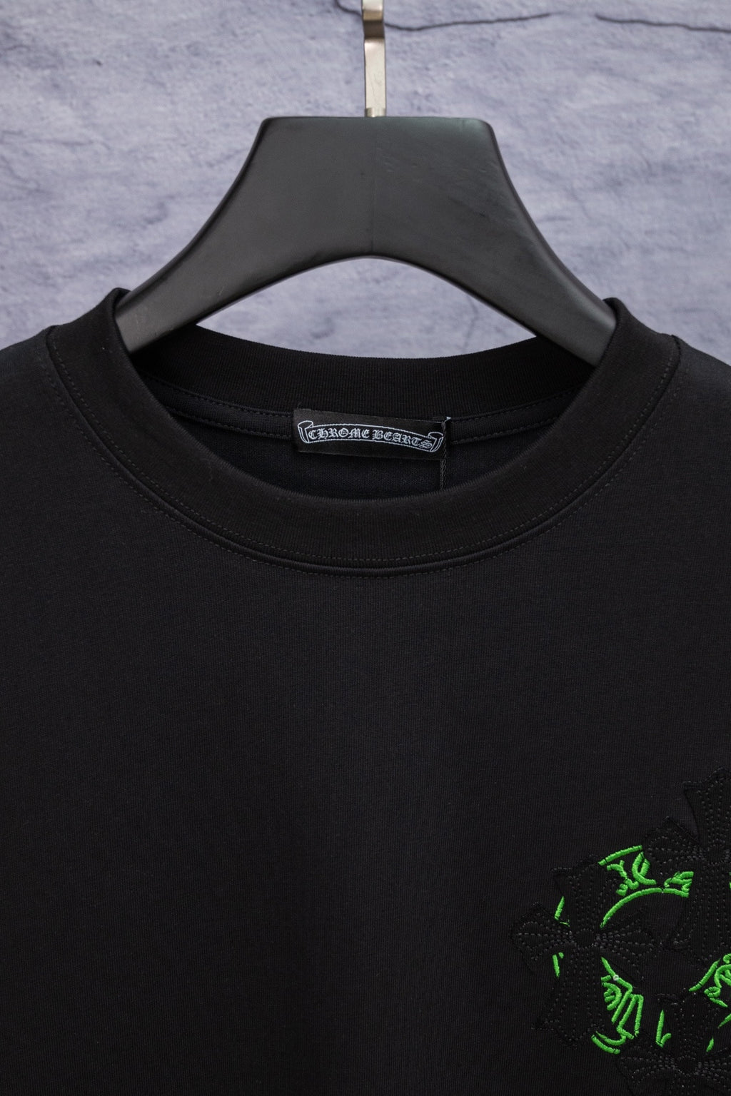 Black crewneck T-shirt with green emblem at right chest