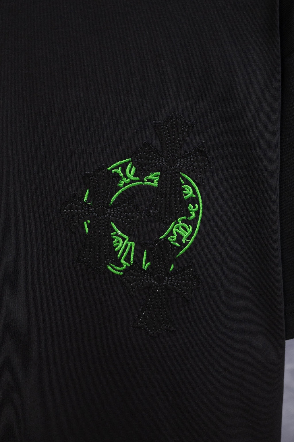 Black T-shirt with large neon-green and dark embroidered emblem