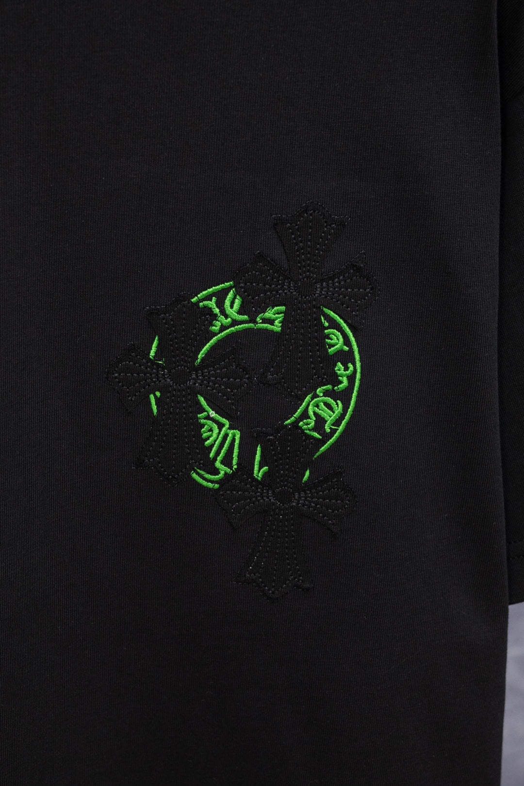 Black T-shirt with large neon-green and dark embroidered emblem