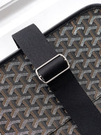 Goyard bag strap detail: black webbing with metal buckle over gray patterned panel