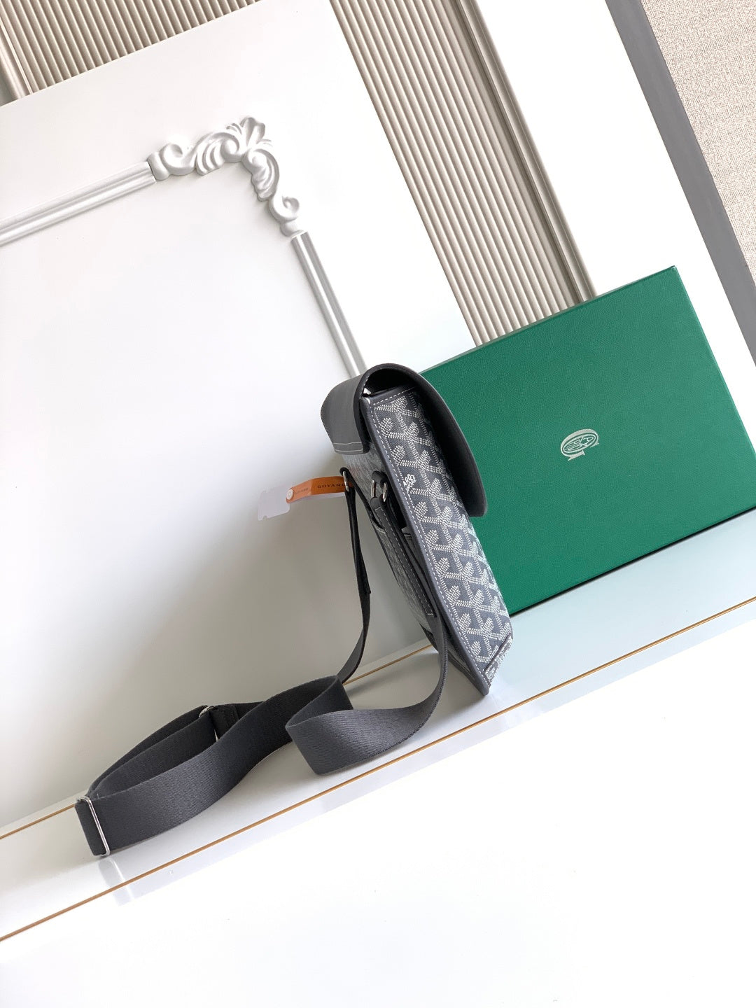 Goyard bag showing side profile with dark strap and gray patterned flap