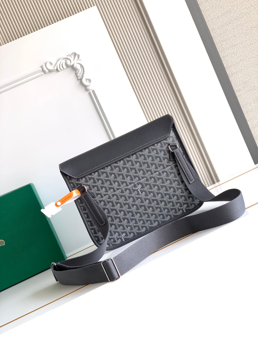 Goyard bag with structured gray body, dark flap, and shoulder strap