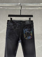 Dark denim jeans with belt loops and a colorful graphic patch on the front right pocket.