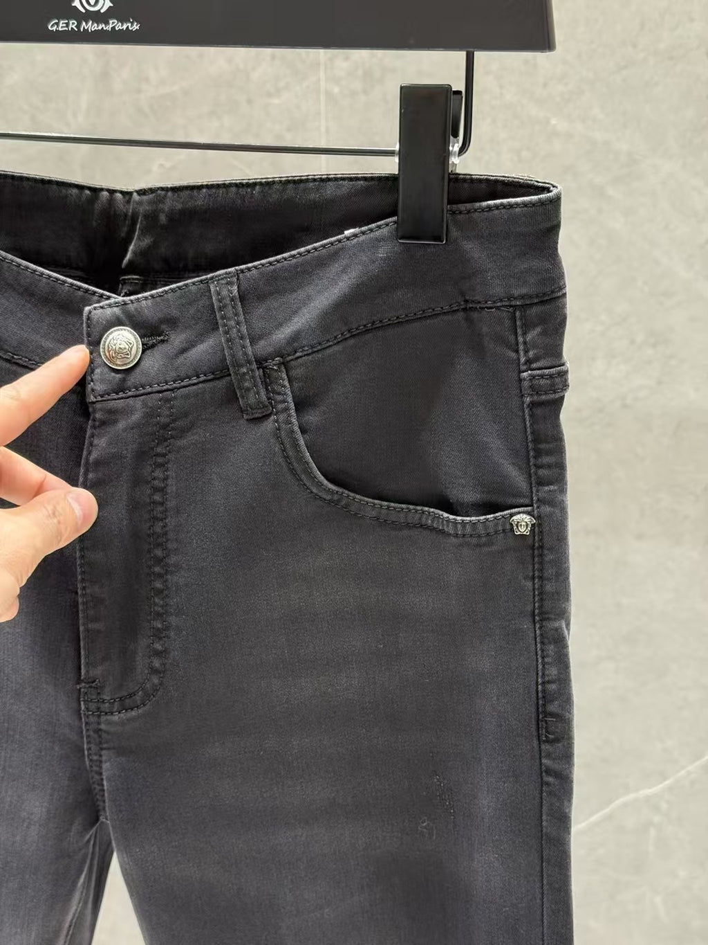 Dark denim jeans close-up with curved front pocket and metal button at coin pocket.