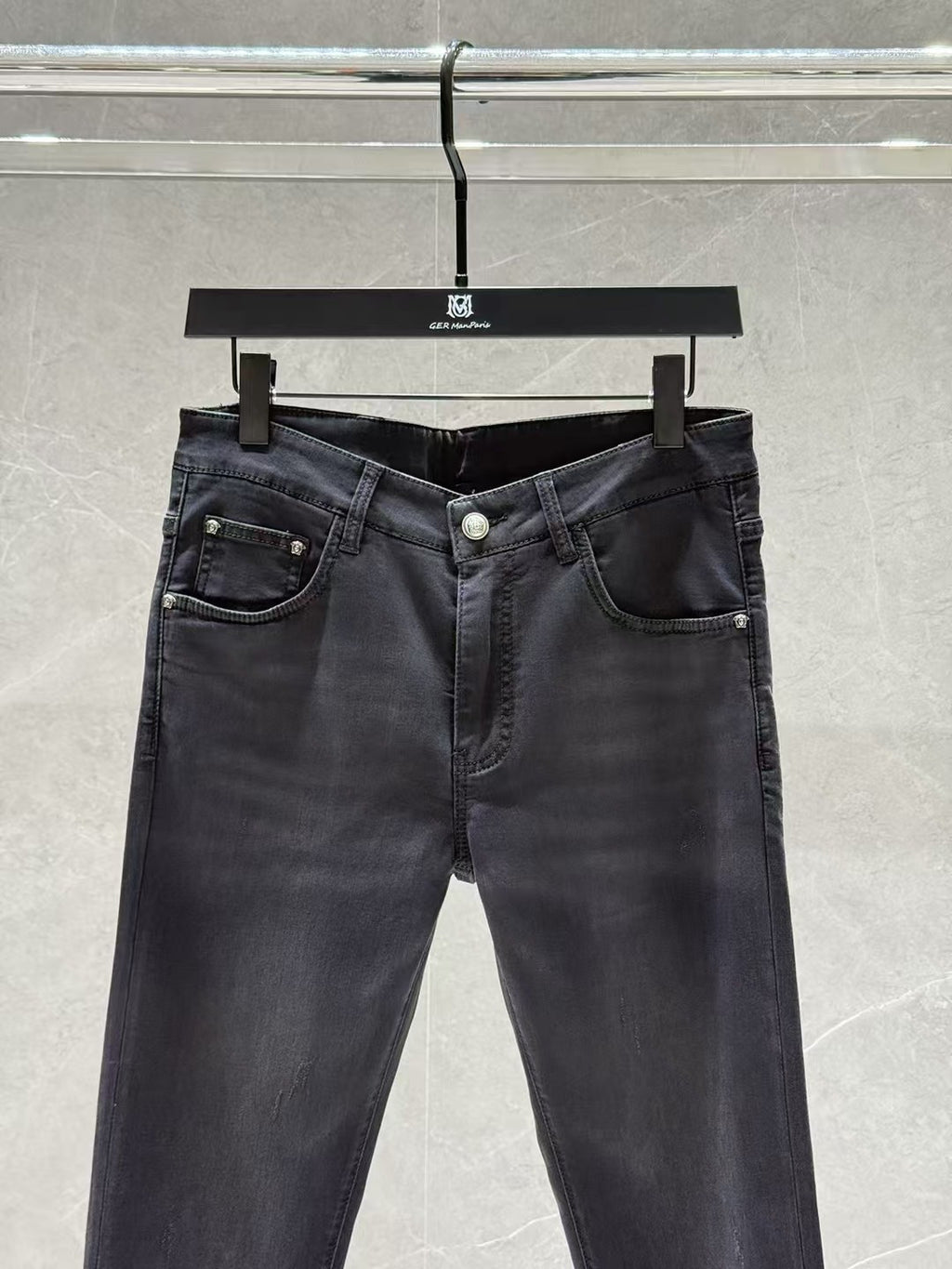 Dark denim jeans with five-pocket layout, visible belt loops, and front button closure.