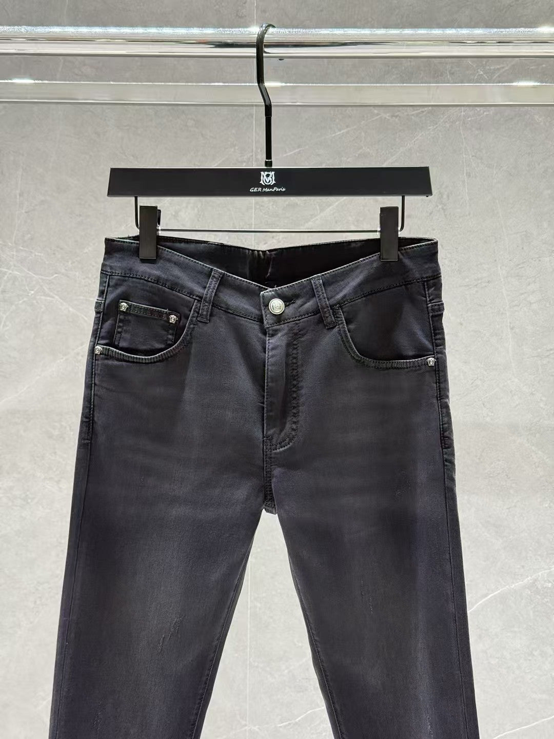 Dark denim jeans with five-pocket layout, visible belt loops, and front button closure.