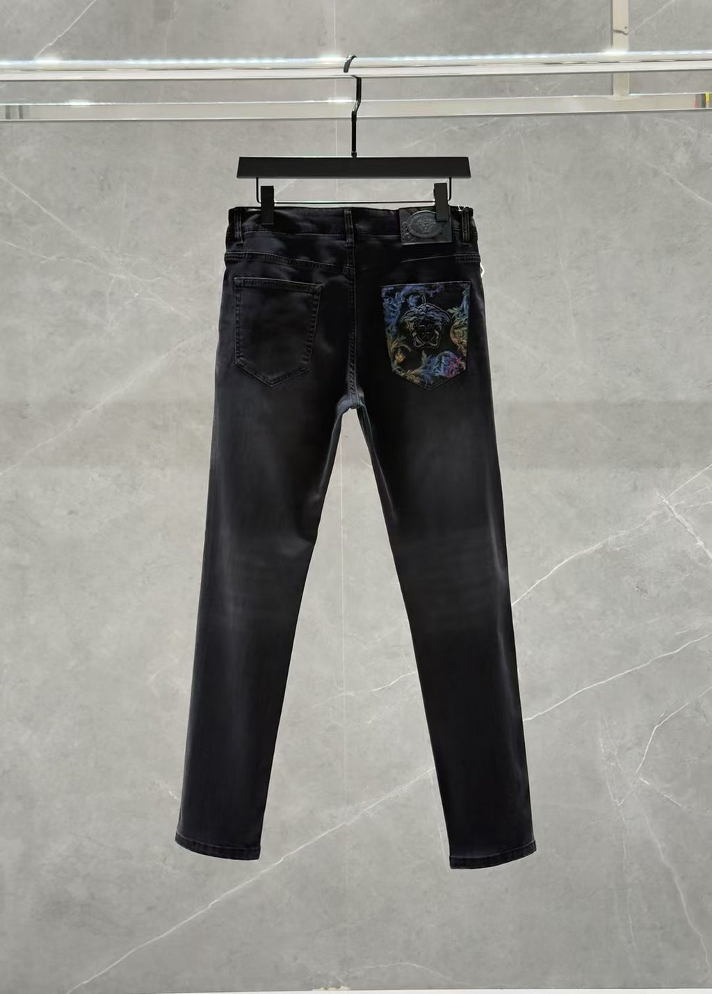 Dark denim jeans with zip fly and a colorful graphic patch on the right leg pocket.