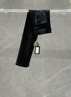Dark denim jeans with a folded hem and colorful graphic patch on the back pocket area.